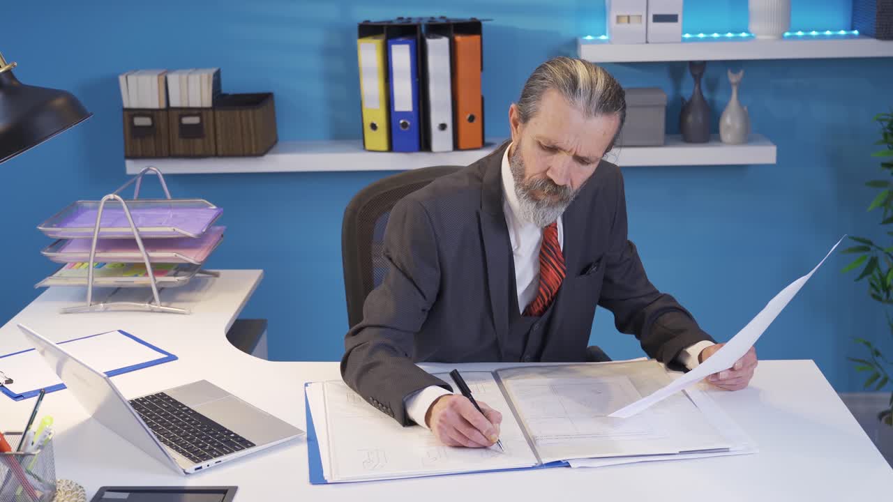hombre de negocios maduro que trabaja en la fabricación de oficinas y la verificación de dibujos de proyectos con enfoque.