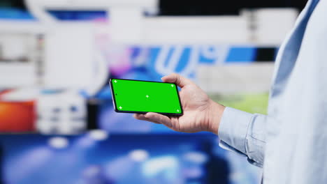 young adult checks green screen on phone as a user interface