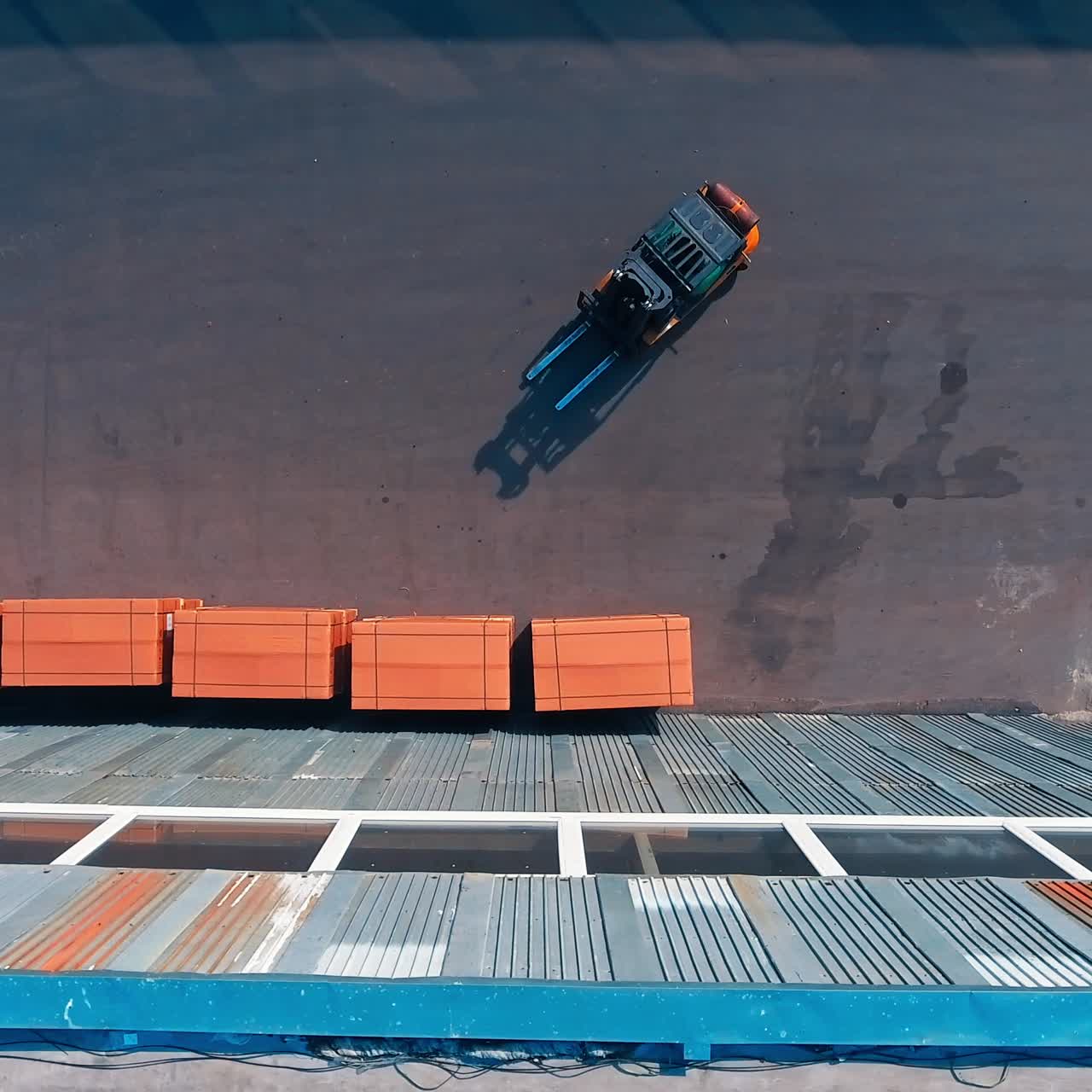 Little loader machine put the boxes in stacks near the metal wall of a hangar. Territory of modern industrial warehouses. Top view