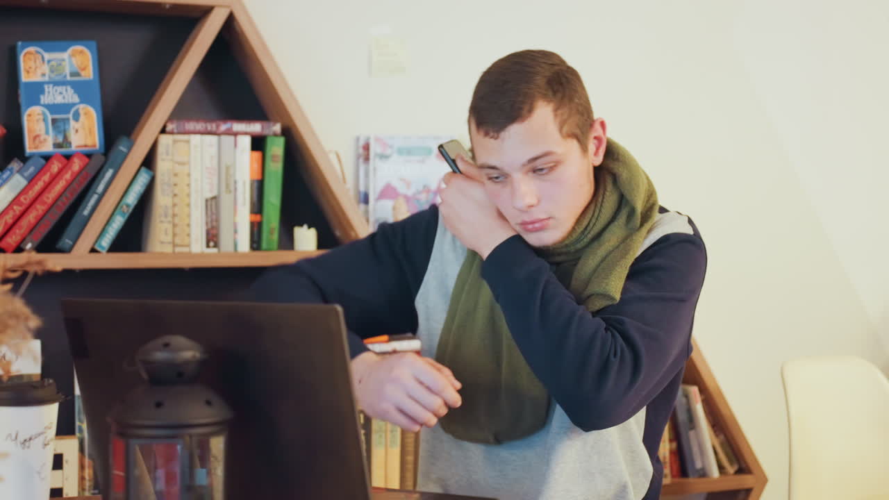 Studente caucasico stanco alla scrivania del portatile, sfondo con libreria, che si strofina gli occhi e allunga un braccio, postura curva che mostra stanchezza, bagliore della lampada e atmosfera notturna, scrittore freelance sotto pressione per una scadenza.