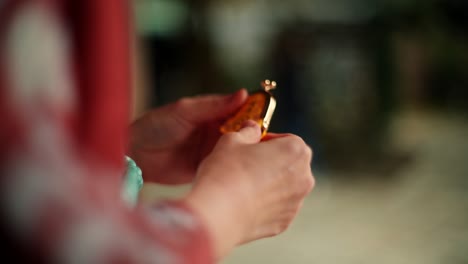 Close-up of hands holding a small, golden object.