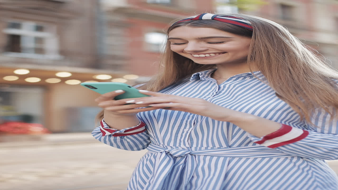 Giovane donna felice che usa lo smartphone e sorride all'aperto.