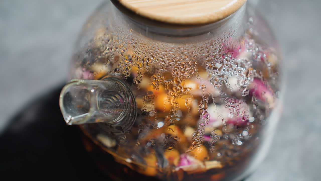 Teapot Handle Closeup, Close View Of Bubbling Floral Tea With Floating Petals And Beads, Detailed Image Capturing Swirling Floral Tea Infusion With Condensation Droplets And Floating Petals