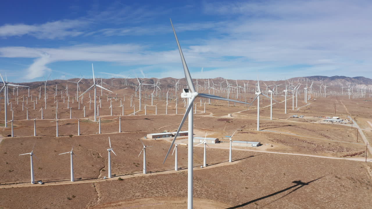 Camera orbits around windmill at solar farm.