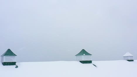 Diapositiva-Aérea-A-Lo-Largo-De-La-Cresta-De-Un-Granero-Con-Tres-Cúpulas-Durante-Una-Tormenta-De-Nieve-A-Cámara-Lenta