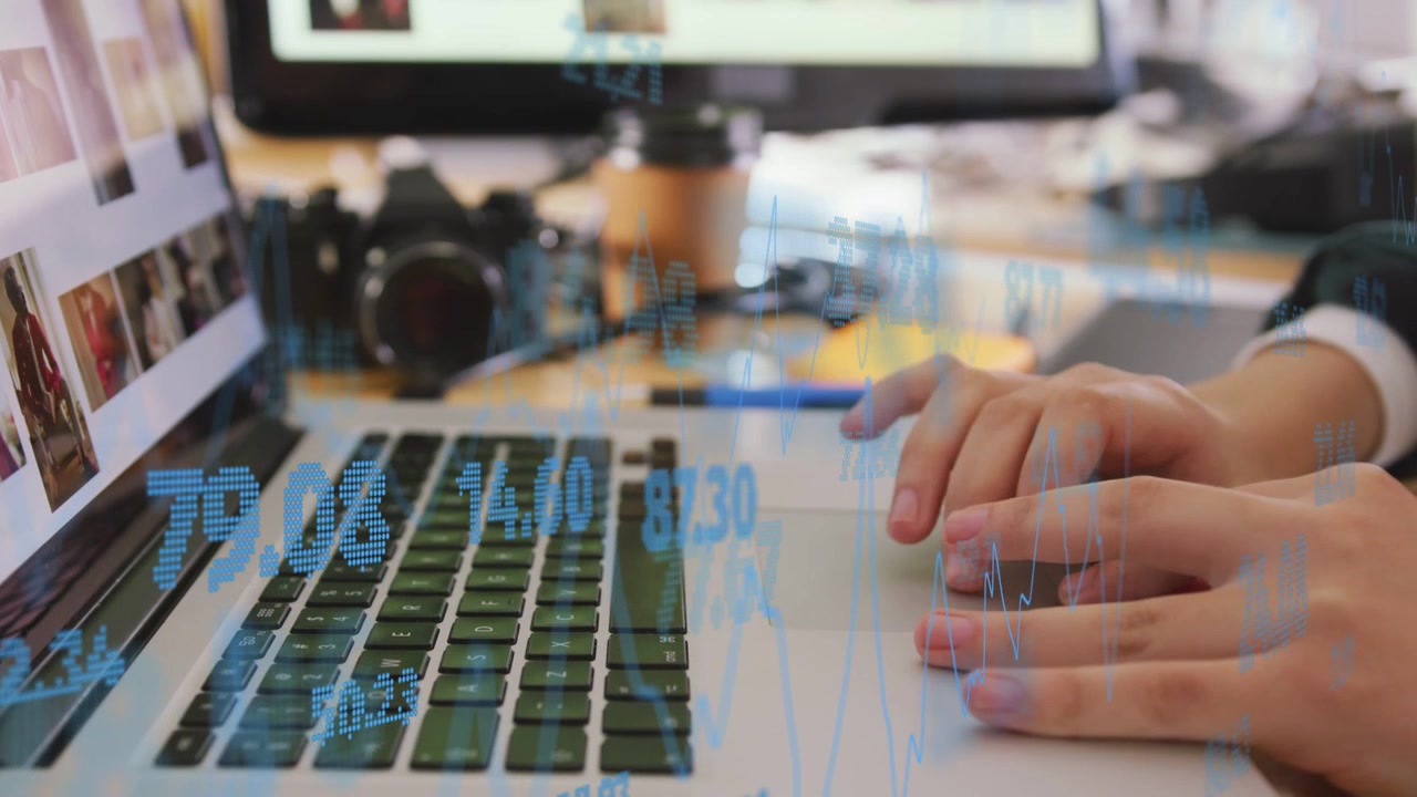 Woman typing while reviewing thumbnails, causing financial graphs animating over keyboard