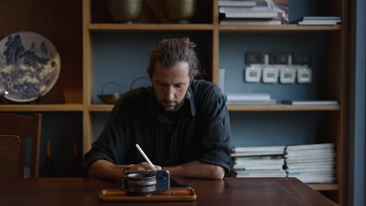 Homme concentré sur son travail numérique avec une tablette et un stylet