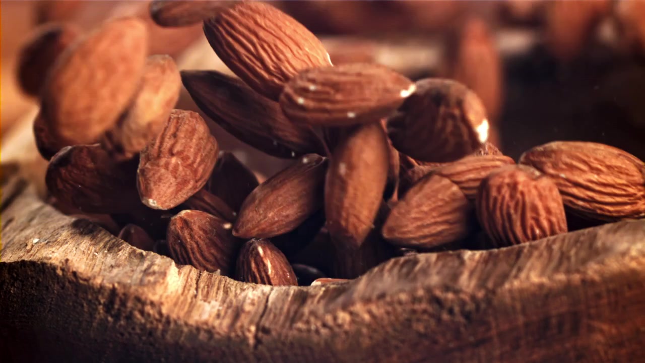 Ralenti : Amandes tombant dans un bol en bois rustique