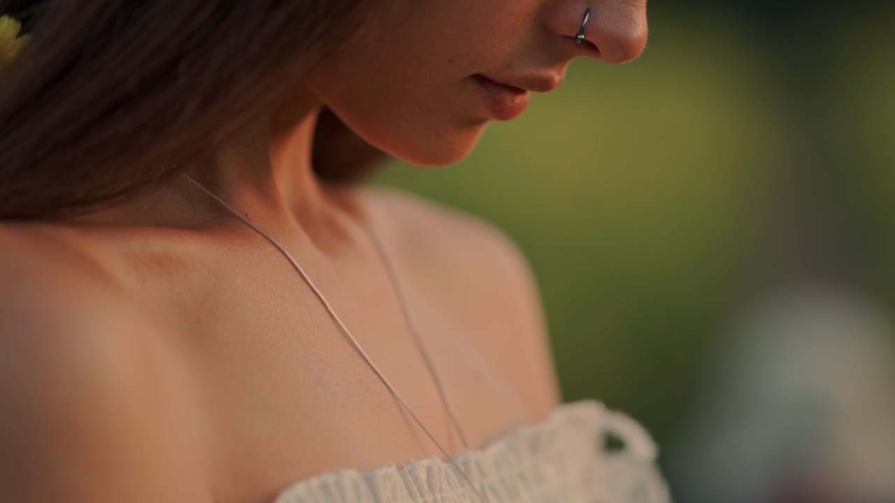 Primo piano di giovane donna che guarda in basso nella luce dell'ora d'oro