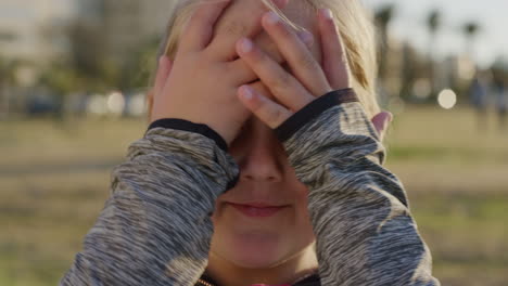 retrato de cerca hermosa niña rubia sonriendo feliz corriendo manos a través del cabello disfrutando de un relajado día de verano en el parque urbano al atardecer