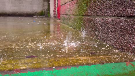 close-up of rain hitting wet concrete surface creating splash in urban setting.