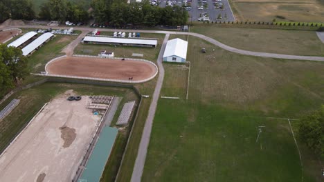 aerial sliding shot of wayne county fairgrounds, horses riding in an outdoor arena