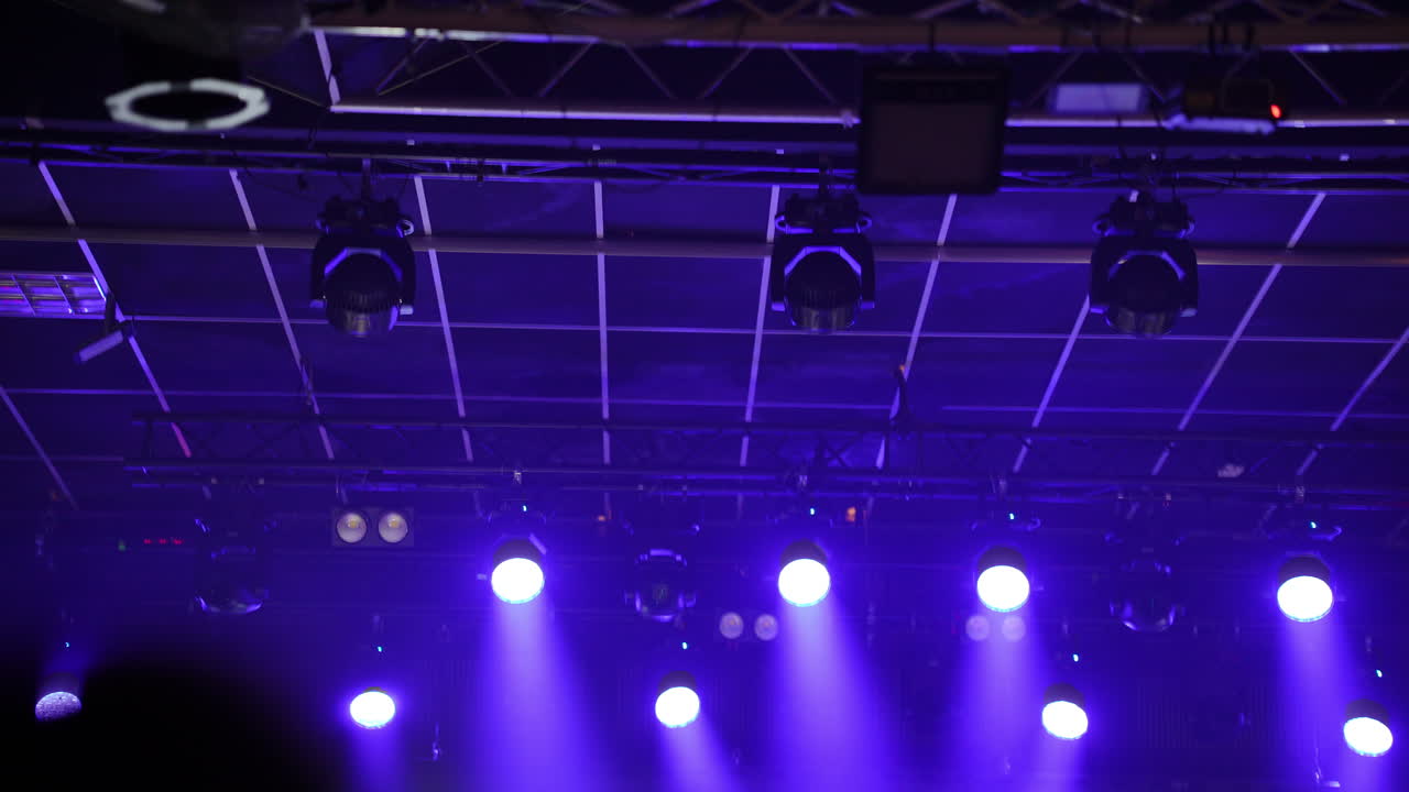 Blurred image of a lively concert scene with musicians performing on stage under vibrant purple lights, capturing the energy and excitement of a live music event