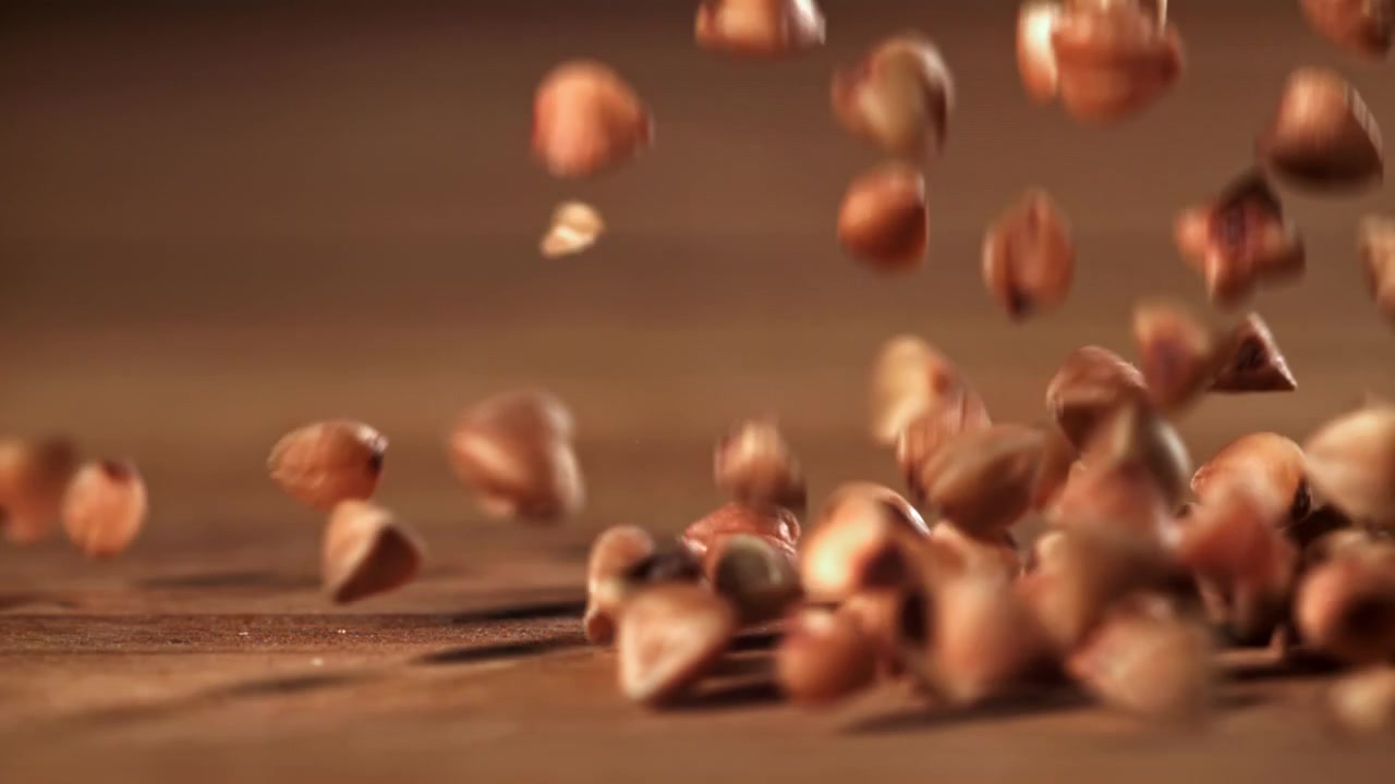 Bokhvetekorn som faller og spretter på en treoverflate i sakte film