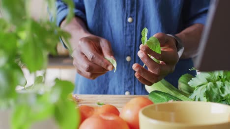 sección media de un hombre afroamericano de pie en la cocina y cocinando la cena