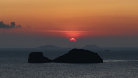 minutes before sun down, behind a whale shape island