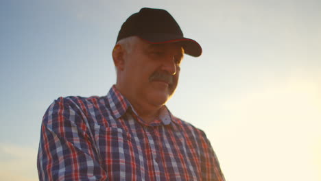 A-close-up-of-a-male-farmer-holds-wheat-in-the-sunlight-and-at-sunset-examines-its-spikes.-Brushes-of-rye-in-sunlight-in-the-hands-of-an-elderly-farmer