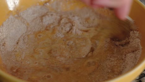 Close-up-of-woman-mixing-eggs-and-flour-with-a-fork-in-a-bowl-to-form-a-batter