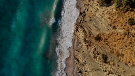 sea waves splashing and foaming on rocky beach, turquoise water texture, top down view