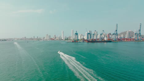 Toma-Aérea-De-Un-Barco-Navegando-Cerca-Del-Puerto-Y-La-Ciudad,-Colombia-Cartagena