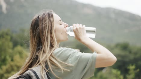 A-woman-drinks-water-from-a-bottle-during-hiking