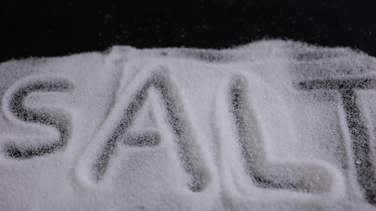 Concetto di ingrediente alimentare con granuli di sale bianco e tipografia materica