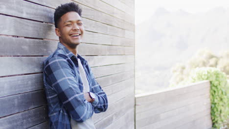 portrait of happy african american man standing on sunny balcony smiling, copy space, slow motion