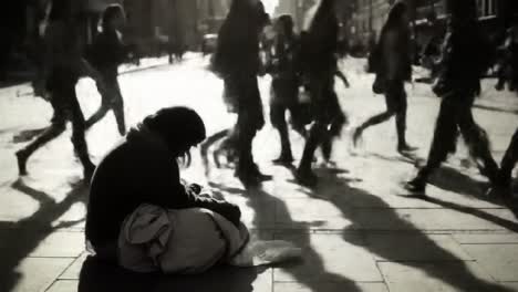 in a busy urban setting, a homeless individual sits on the sidewalk, wrapped in layers against the cold. passersby rush by, unaware of the stark contrast in their lives.
