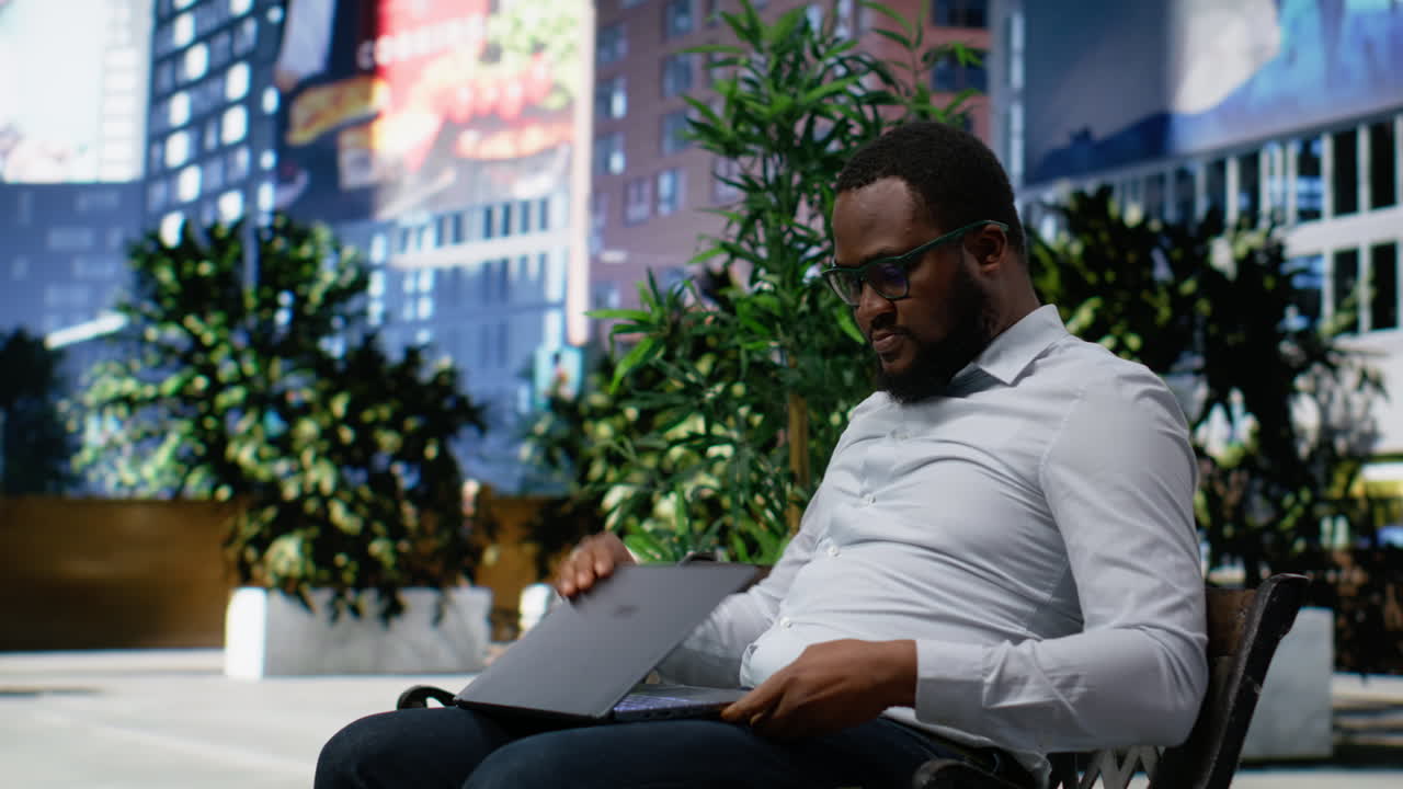 Black man working remotely on his laptop in a park bench setting