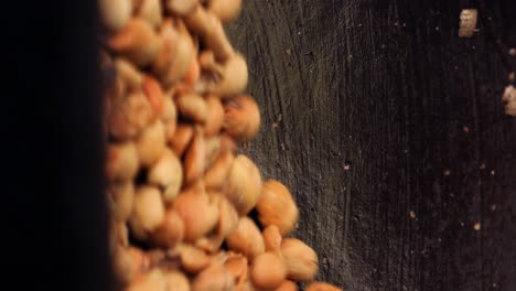 vertical slow motion shot of expensive and exclusive kopi luwak coffee beans being stirred and roasted in a wok with a wooden spoon in bali indonesia