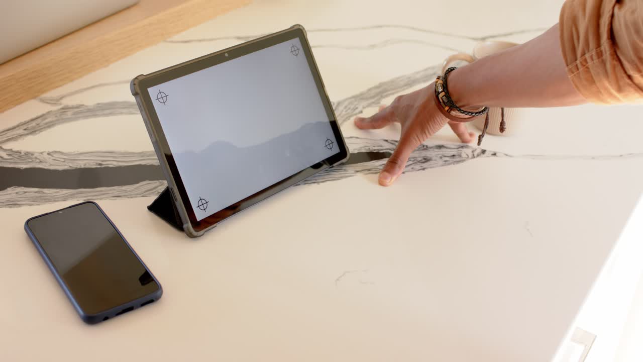 At start, hand is sliding inward and is tracing marble pattern beside tablet to explore texture