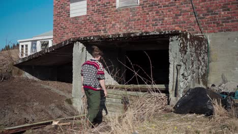 Man-Removing-Old-Wooden-Wall-Of-Basement