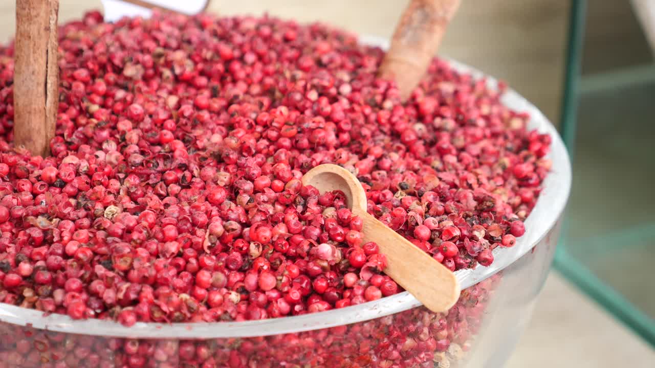 Grains de poivre rose avec cuillère en bois et bâtons de cannelle