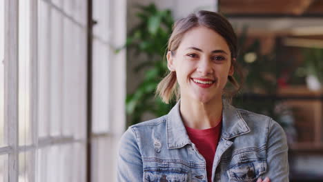 millennial hispanic female creative standing in office smiling and laughing to camera, close up