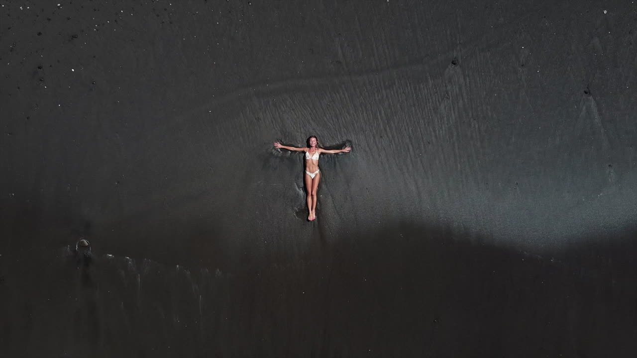 mujer relajándose en una playa de arena negra