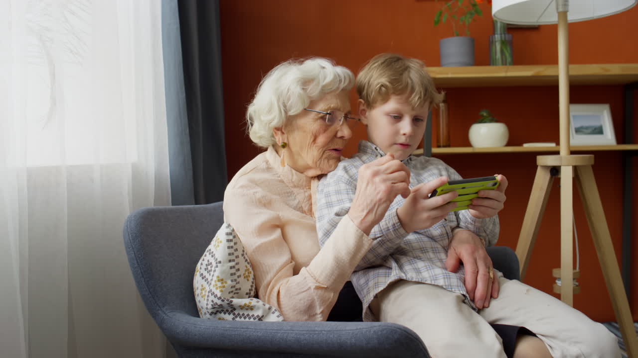 Boy Sitting with Grandma and Playing on Console
