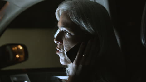 Profile-View-Of-Gray-Haired-Woman-Talking-On-Phone-In-A-Car