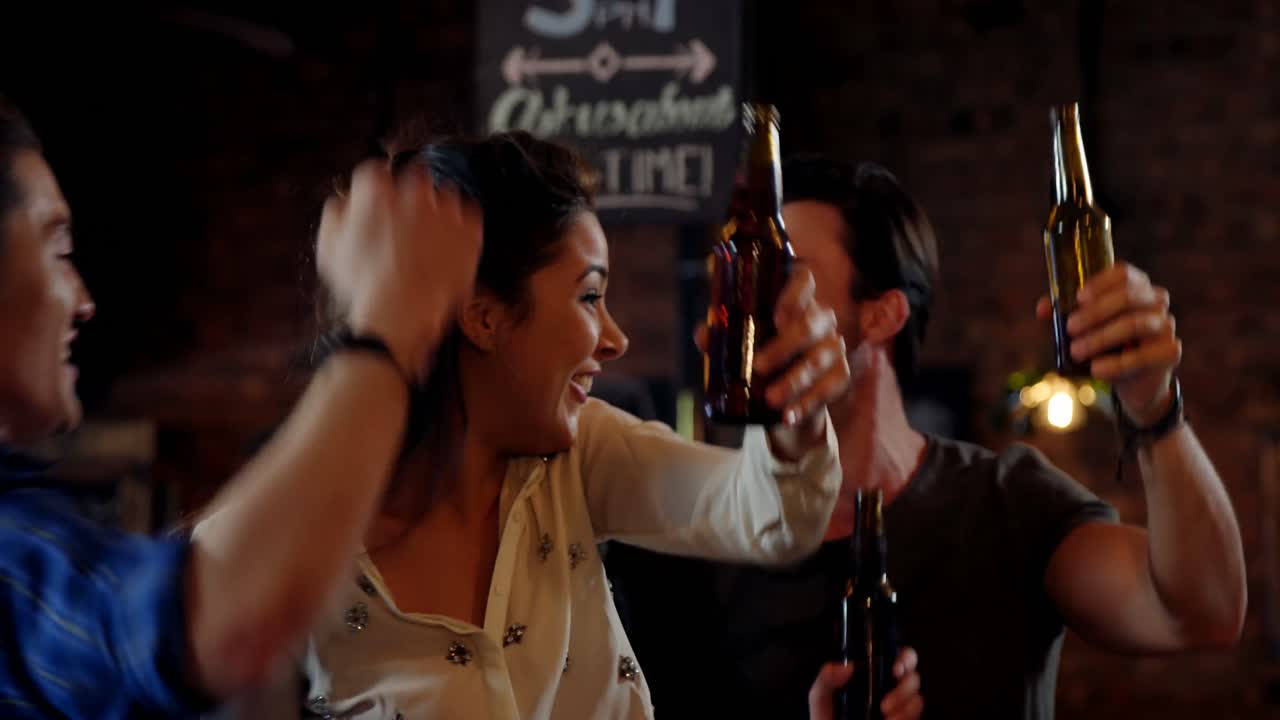 grupo de amigos interactuando mientras brindan botellas de cerveza
