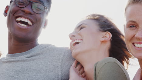 Head-And-Shoulders-Portrait-Of-Smiling-Young-Friends-Outdoors-Together-Against-Flaring-Sun