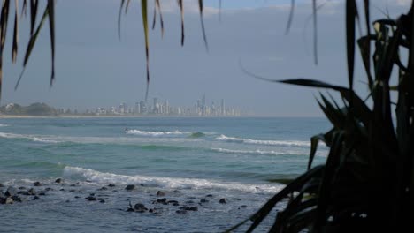 Rompiendo-Las-Olas-Del-Mar---Playa-De-Burleigh-Heads-Con-Paisaje-De-Ciudad-Distante-En-Gold-Coast,-Queensland,-Australia