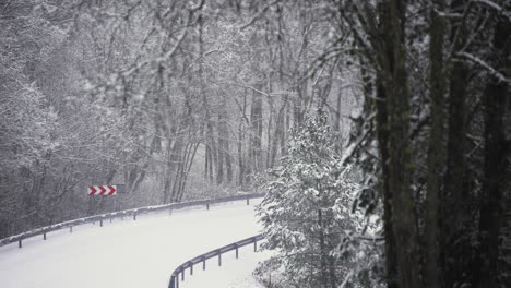 snow covered road with sharp bend and warning sign, long shot