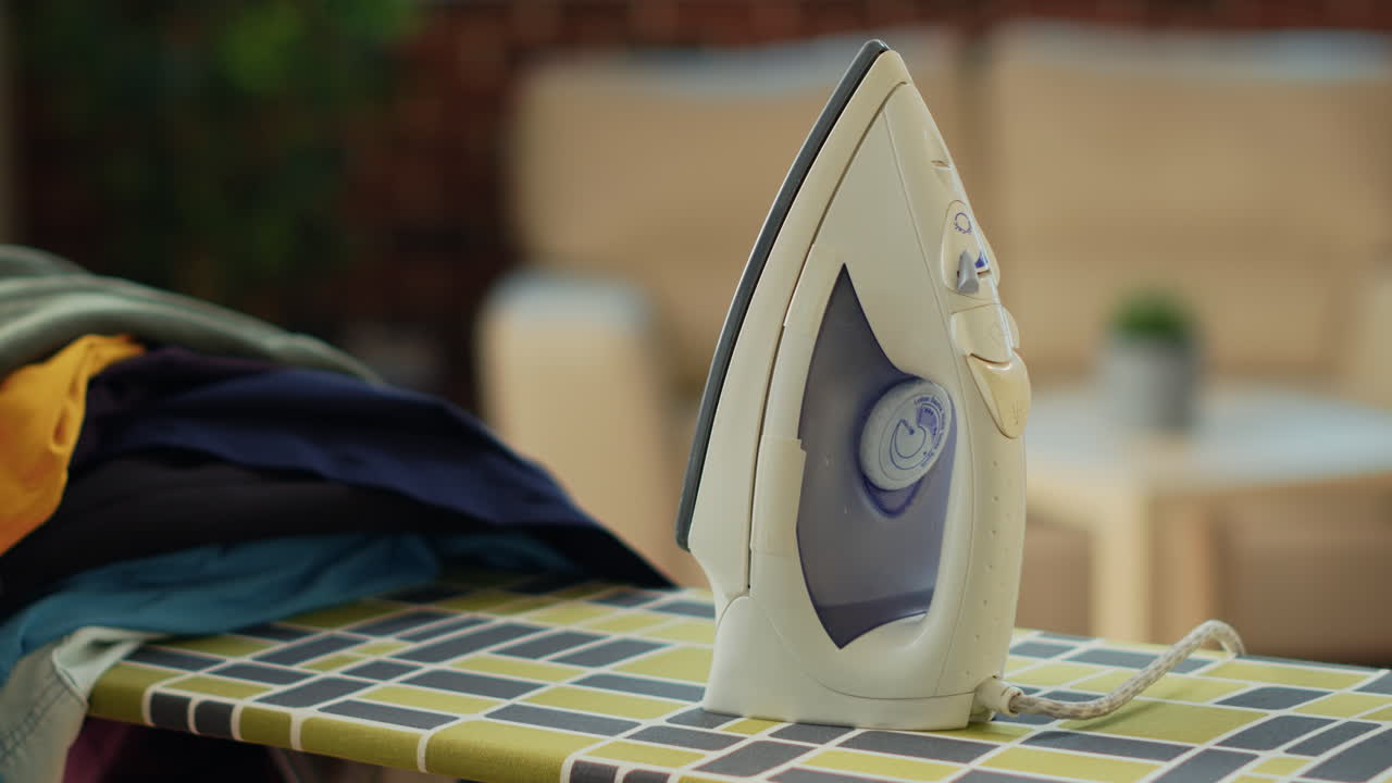 Iron tool placed on ironing board with pile of washed clothing