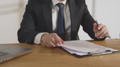 businessman in office reviewing and making notes on application or cv for job vacancy 1