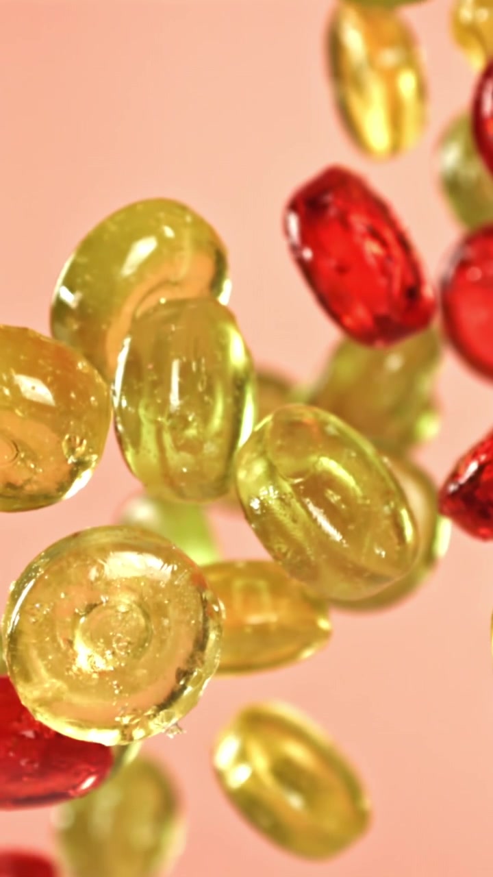 Caramelle colorate e traslucide che cadono e fluttuano al rallentatore
