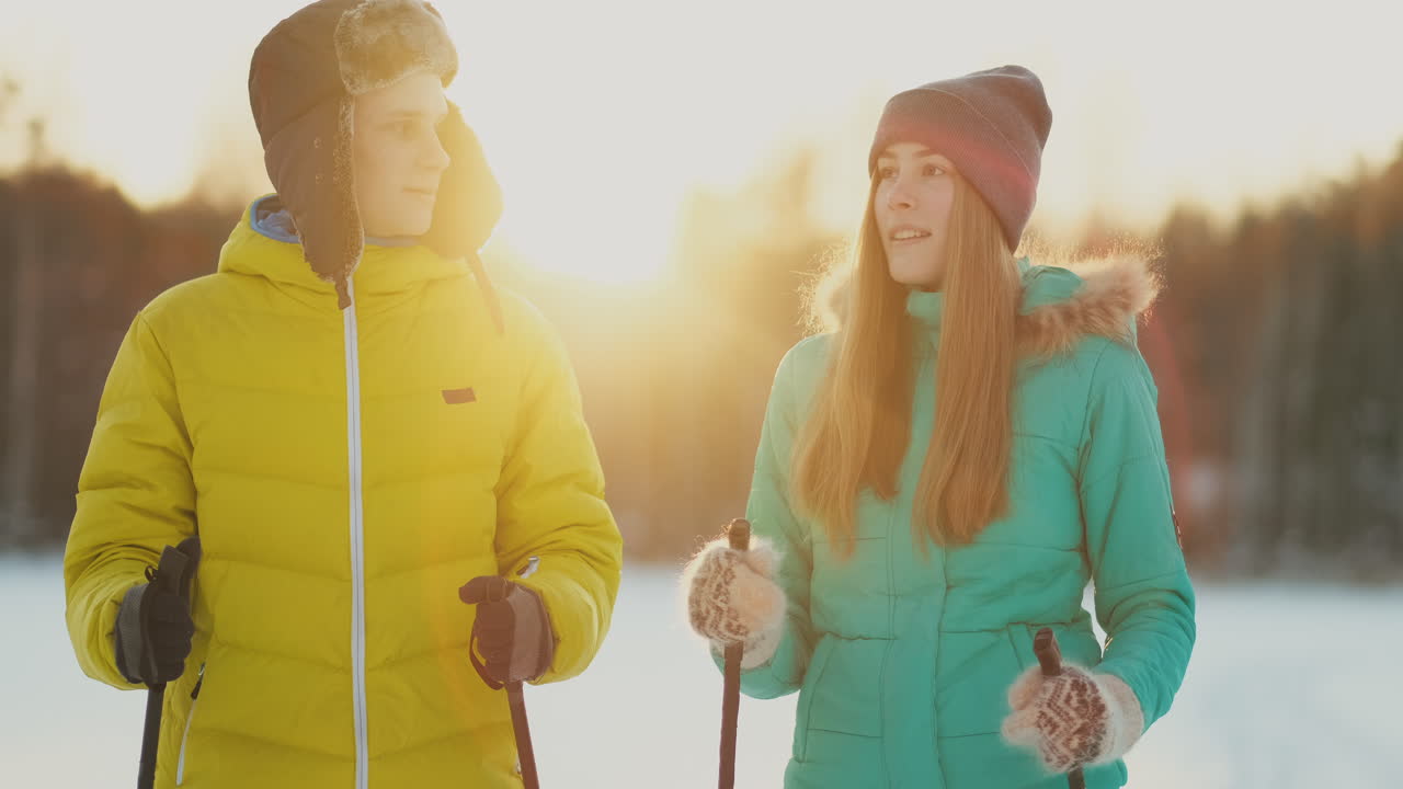 A man embraces a woman standing in the woods at sunset after a winter walk on skis. St. Valentine's Day. Romance and warm feelings of lovers. Slow motion