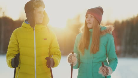 un hombre abraza a una mujer parada en el bosque al atardecer después de un paseo invernal con esquís. calle. día de san valentín. romance y cálidos sentimientos de los amantes. camara lenta