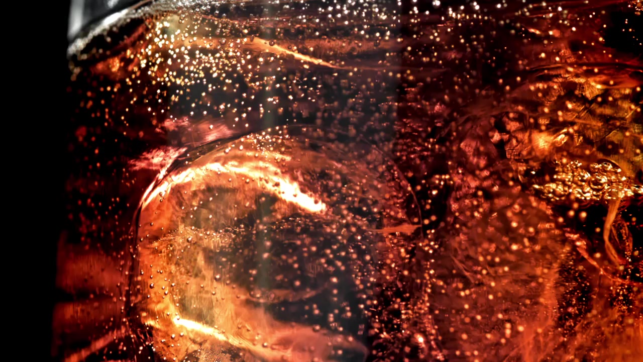 Macro di cola frizzante con cubetti di ghiaccio in un bicchiere