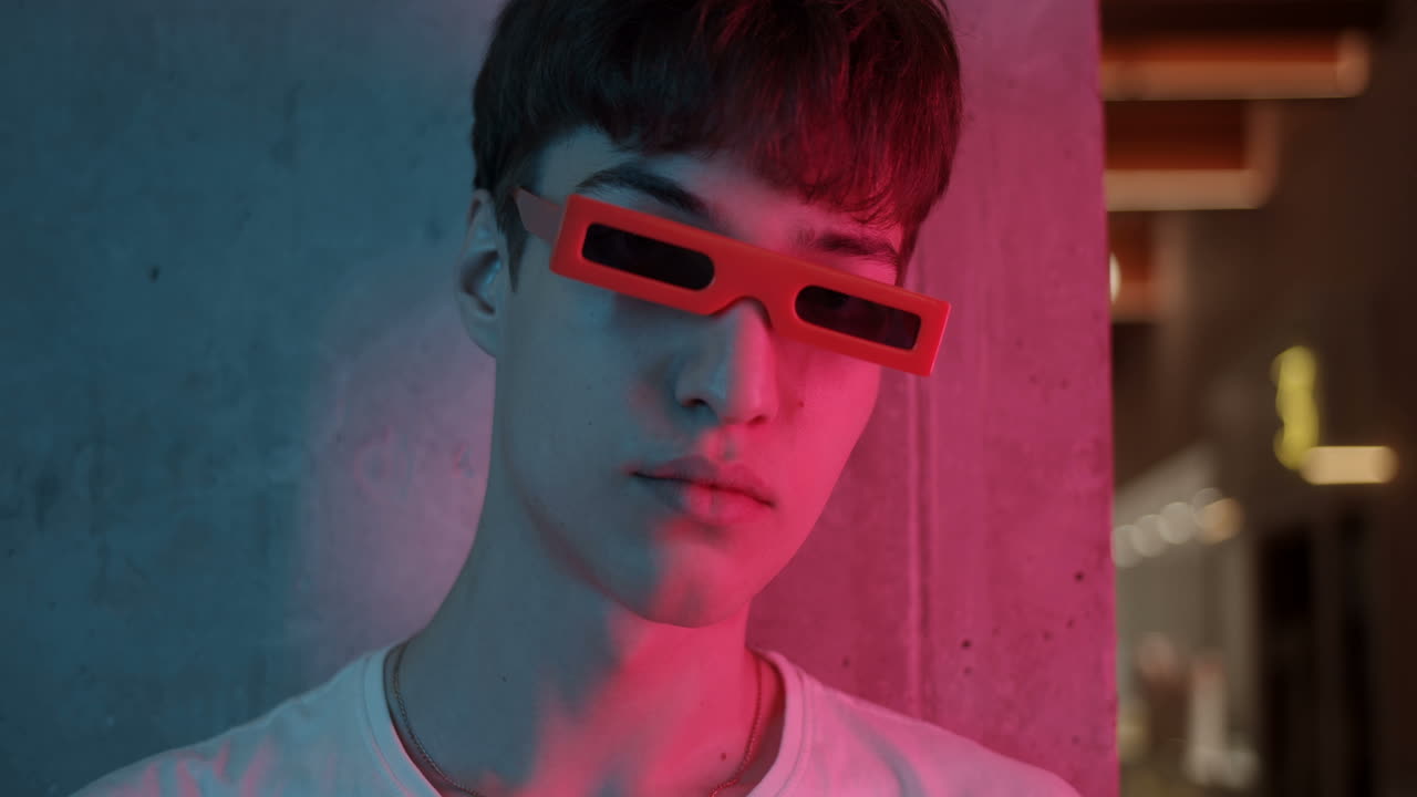 Portrait of a Young Man with Red Glasses in Neon Lighting