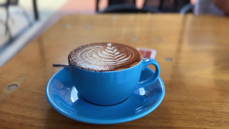 Cappuccino coffee, latte art milk foam design inside restaurant, blue mug