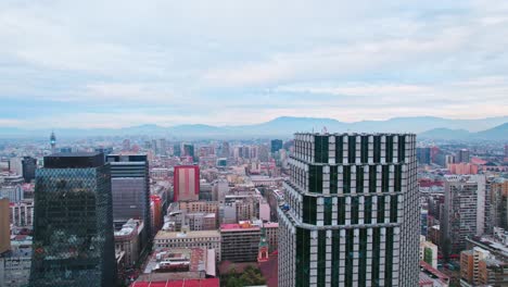 flyover of the centennial tower in contrast with the old architecture of downtown santiago chile, on a cloudy morning